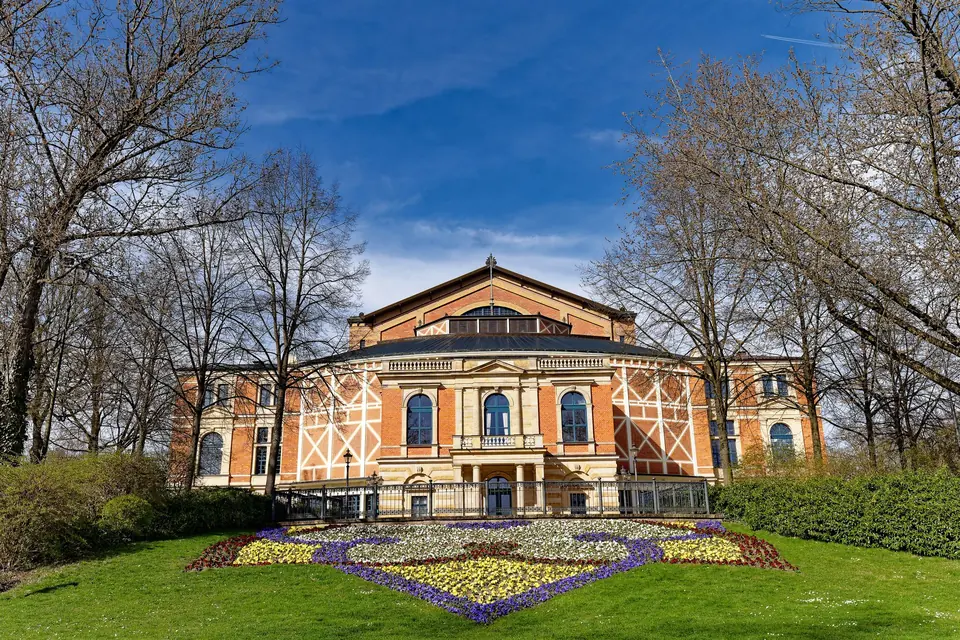 Blick auf die Bayreuther Festspielhaus mit einem bunten Blumengarten im Frühling.