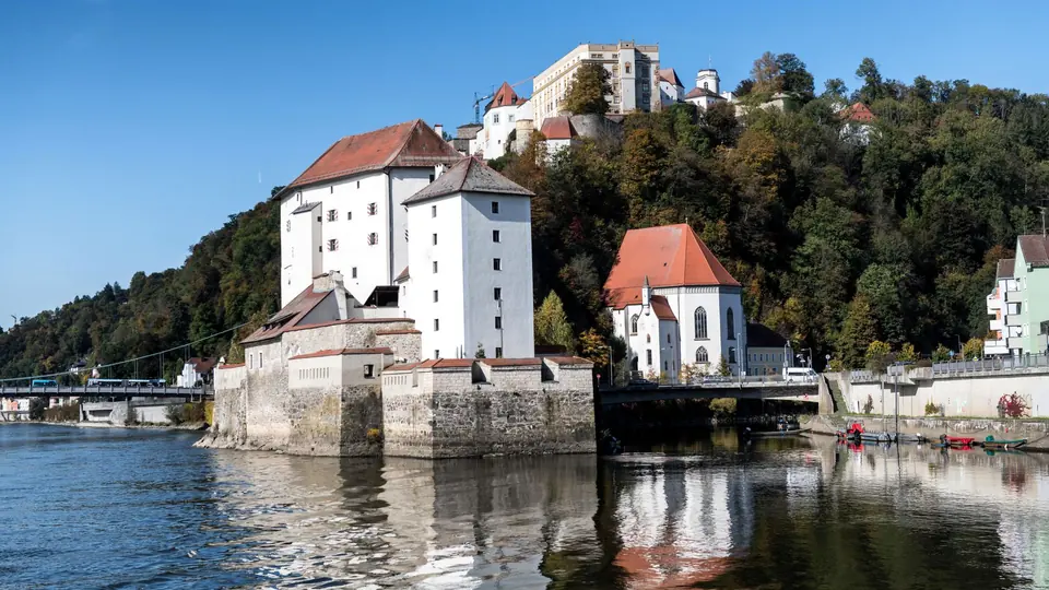 Entdecken Sie die historische Schönheit der Burgen von Passau, die sich im ruhigen Wasser des Flusses spiegeln.